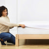 An image of the Waterproof Mattress Protector with a woman pulling the protector across the surface of a mattress